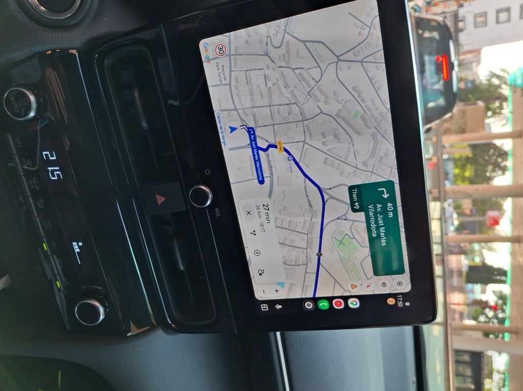 A car's dashboard display showing a navigation map, with a highlighted route, estimated time, and distance to the next turn.